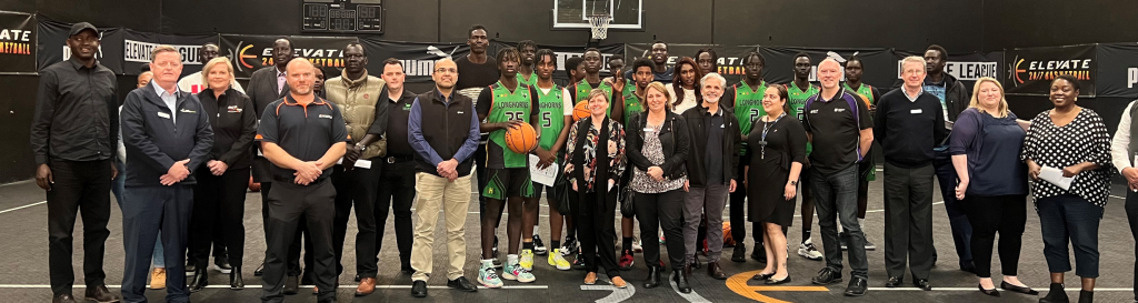 Group photo of basketball players and officials at an event.